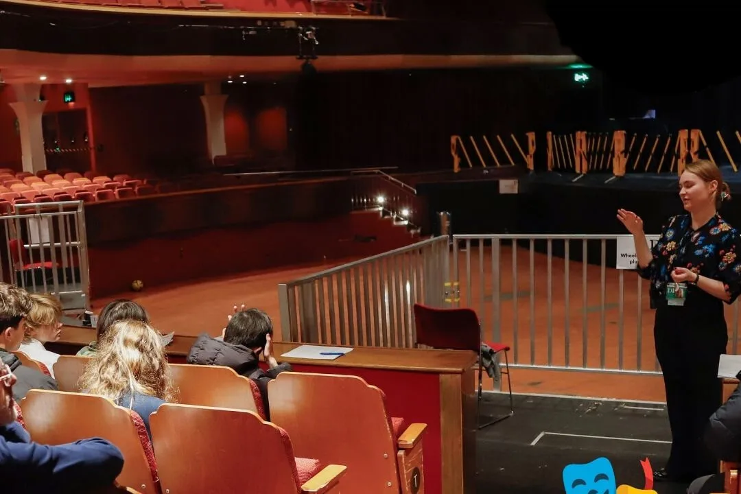 Audience members sit in a theatre auditorium while a presenter speaks from the front near the stage. The image includes logos for Creative Access, Discover Creative Careers, Future Creators, and Creative Careers Hub, along with overlaid text that reads: “Looking to get into theatre & live events but don’t know where to start?” and theatre mask icons.